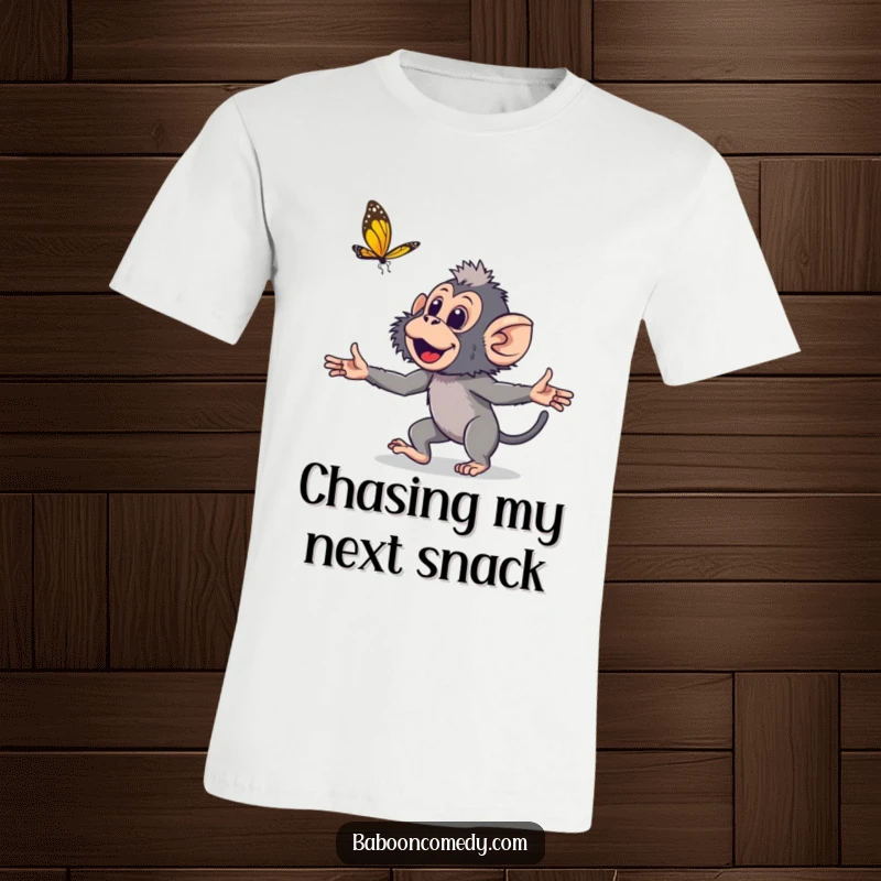 Funny young baboon t-shirt depicting a cute primate with arms wide, joyfully pursuing a delicate butterfly in a lighthearted design.